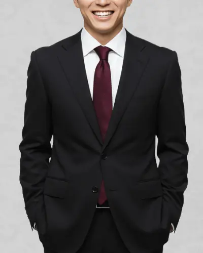 黒服の男性が笑顔で立っている写真